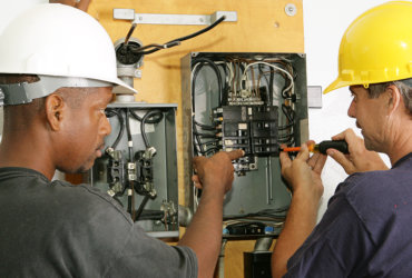 two man repairing breaker panel